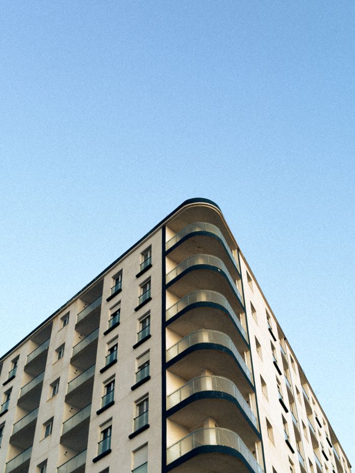 Low-angle view of a modern apartment building with balconies against a clear blue sky.